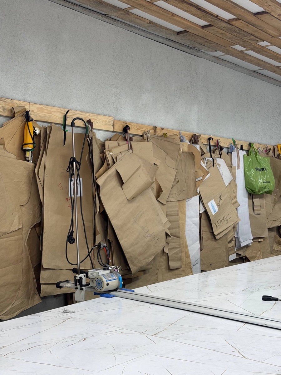 Paper patterns and sample garments hanging on the workshop wall