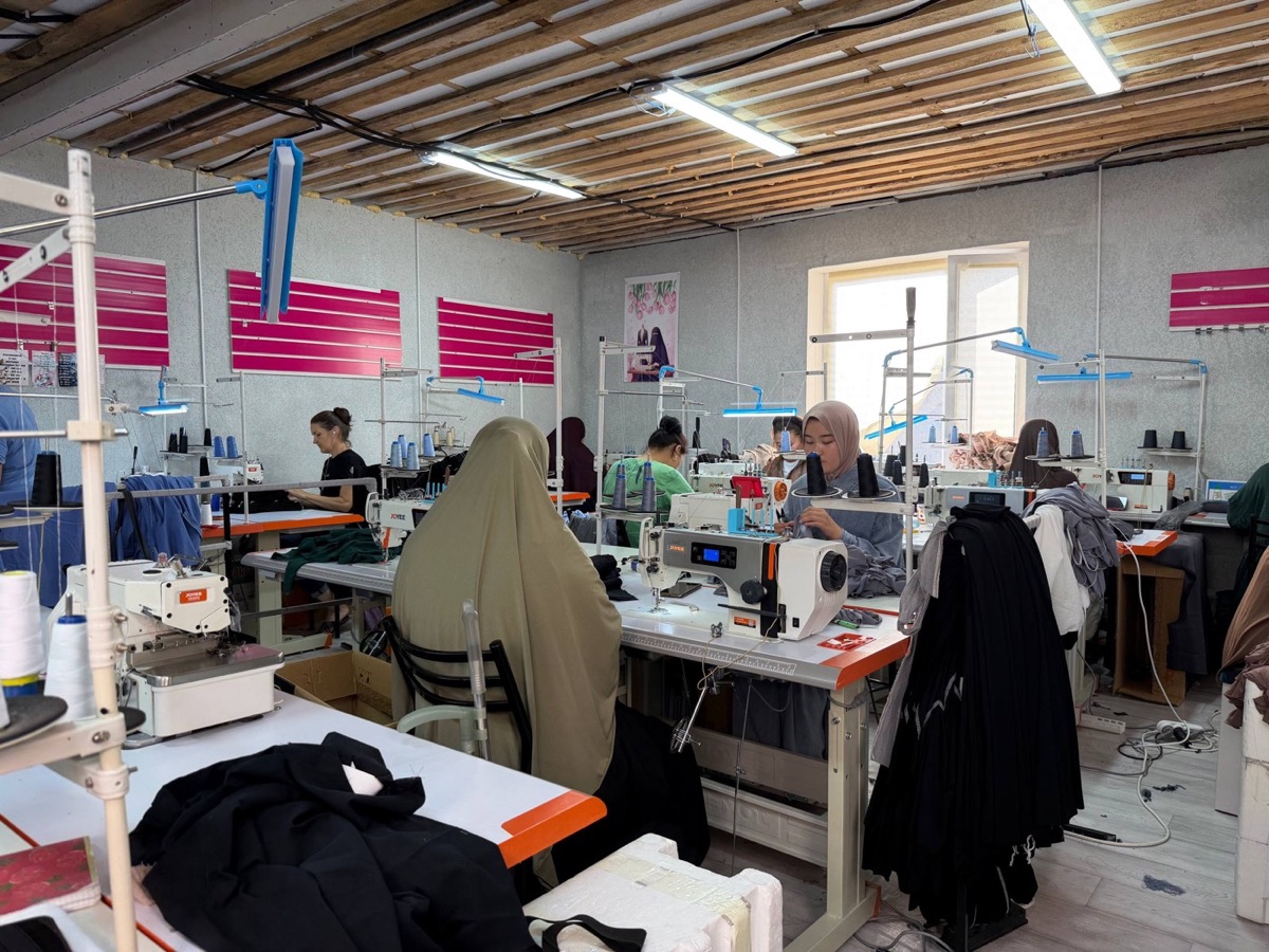 Seamstresses at industrial sewing machines in a bright workshop